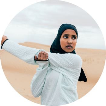 A woman standing in a dessert and stretching her hands